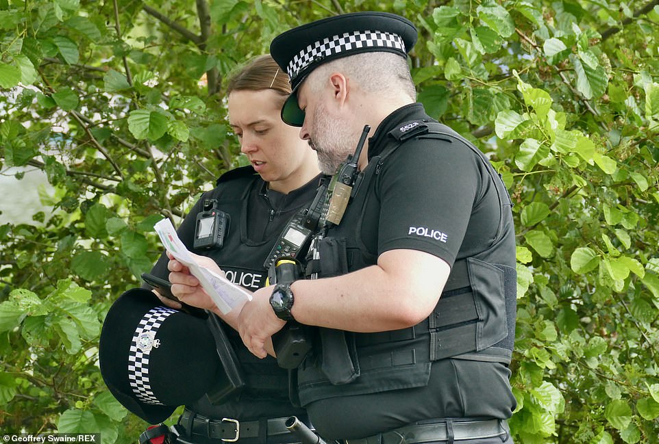 Two police officers are seen studying the festival site map in Reading, Berkshire, ahead of the three-day event this weekend