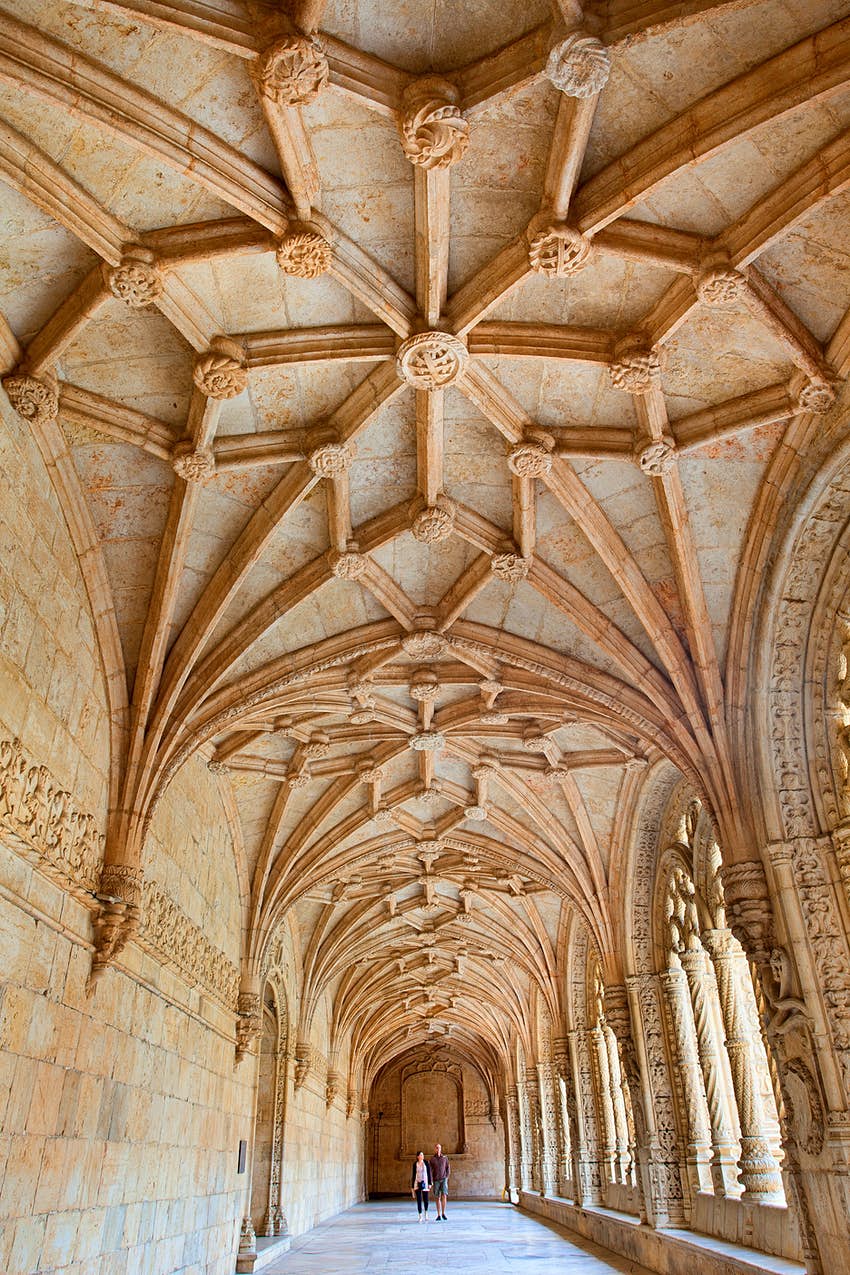 Tourists admiring a vaulted ceiling in a monastery
