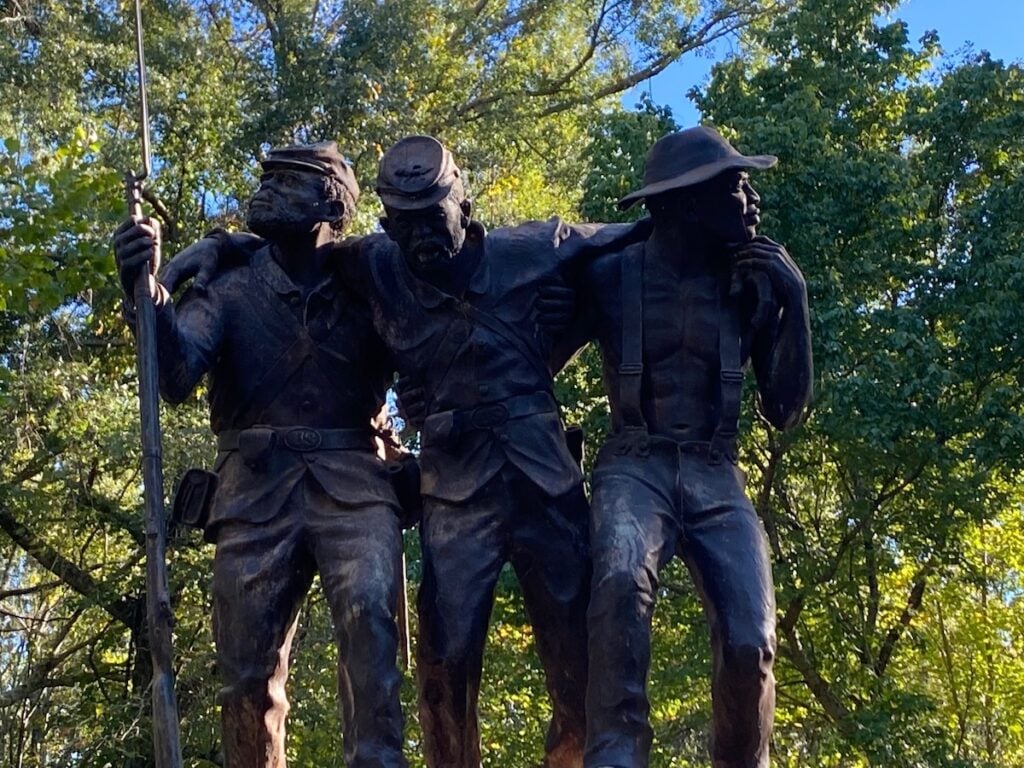 statue of two men holding up man in the middle