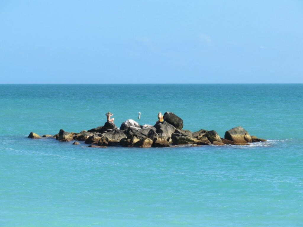 two women sunbathe on rocks in the blue waters of Key West off of Fort Zachary Taylor Beach