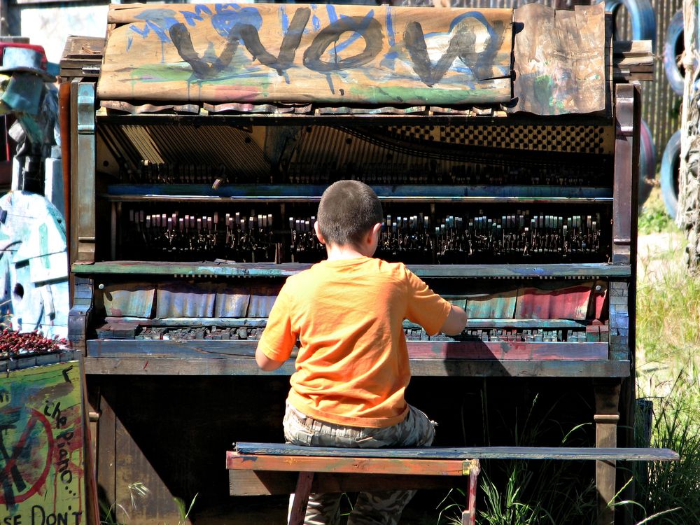 A kid playing a piano at Adventure Playground