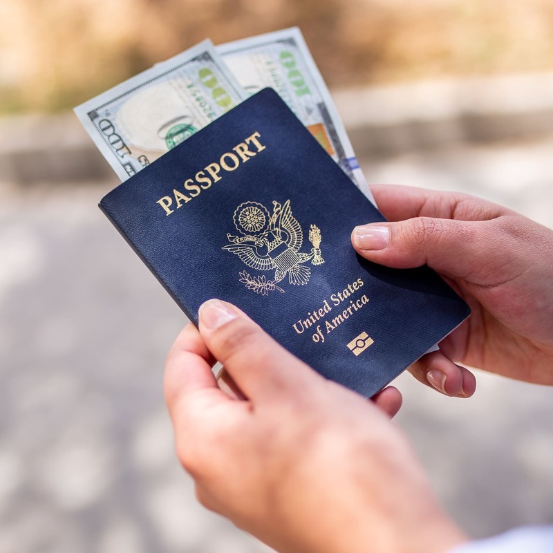 An American Citizen Holding A US Passport With Dollar Bills Inside