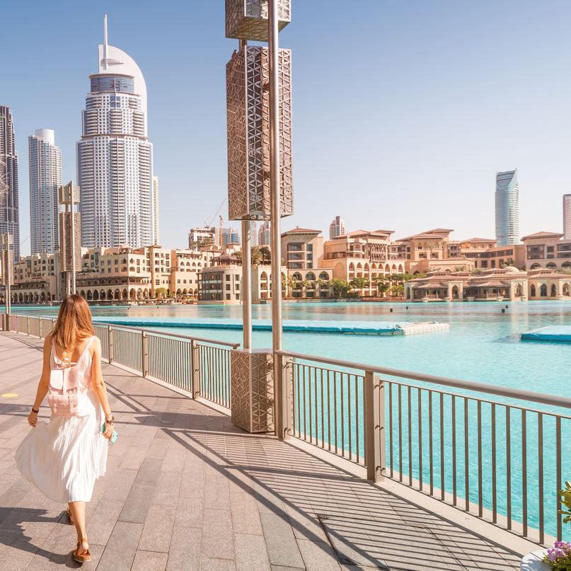 Woman walking along the water with dubai in the background