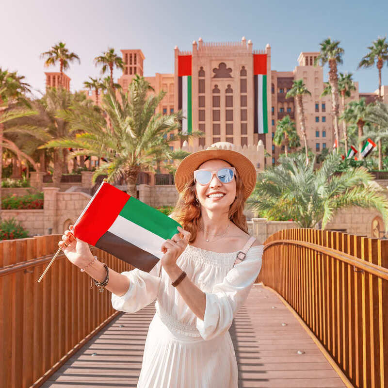 Young Female Tourist Holding Up A UAE United Arab Emirates Flag In Dubai, United Arab Emirates, Middle East, Western Asia