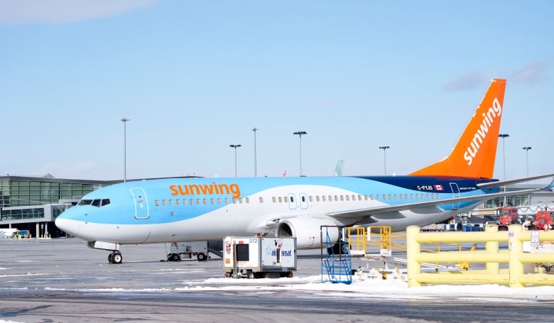 A Sunwing aircraft is seen parked on the tarmac of an airport. 